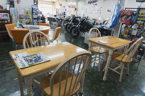 店内には作業が終わるのを待つスペースとしてテーブルと椅子が3セット備えられていて、オートバイや洋品が並んでいる