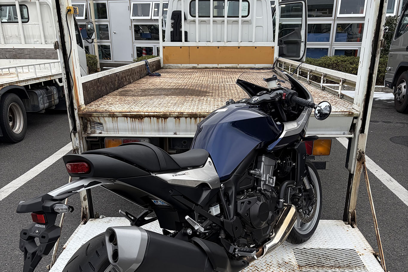 トラックの荷台からリフトで降ろされるオートバイ